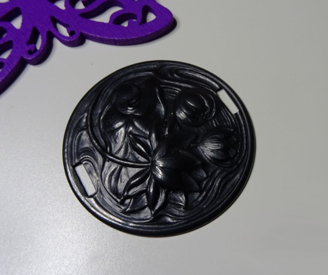 Water lily medallion in black metal relief with side ties 